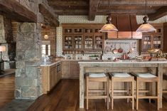 a large kitchen with wooden floors and stone walls, along with an island in the middle