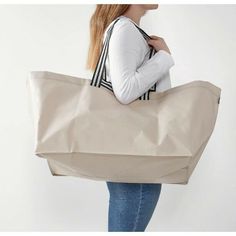 a woman carrying a large beige tote bag