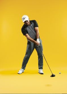 a man in black shirt and grey pants playing golf on yellow background with white hat