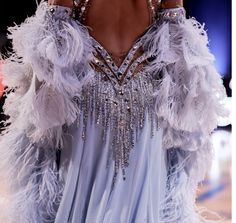 the back of a woman's dress with white feathers and beading on it