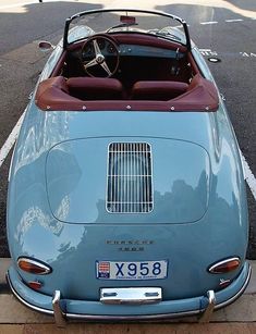 an old blue sports car parked in a parking lot