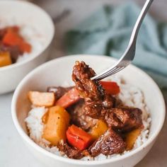 two bowls filled with meat and vegetables on top of white rice next to a fork