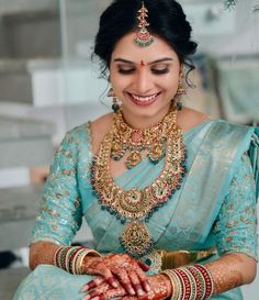 a woman in a blue sari is smiling and holding her hands on her chest