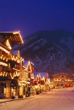 a snowy street lined with christmas lights and buildings