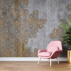 a pink chair sitting next to a plant in front of a wall with geometric designs on it