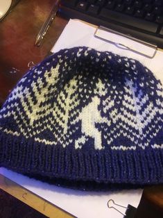 a blue and white knitted hat sitting on top of a desk