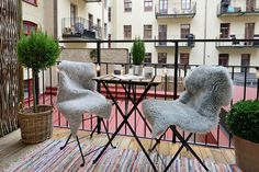 two chairs sitting on top of a balcony next to a table and potted plant