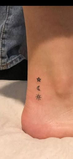 a woman's foot with three small stars and moon tattoos on the side of her ankle