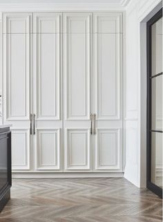 an empty room with white cabinets and wood floors