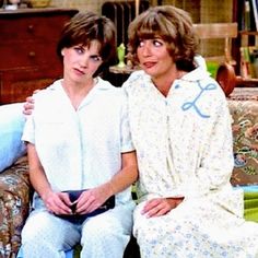 two women in pajamas sitting on a couch