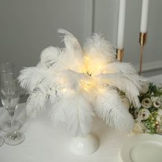 a white table topped with a vase filled with flowers next to two wine glasses and candles