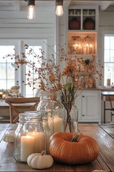 candles and pumpkins are sitting on a wooden table in the middle of a kitchen