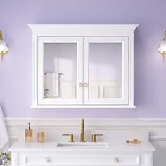 a bathroom with purple walls and gold fixtures on the cabinet above the sink is white