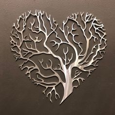 a metal heart shaped tree with branches cut out of it's sides, on a wall