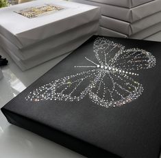 a black canvas with a butterfly on it sitting on a table next to other white boxes