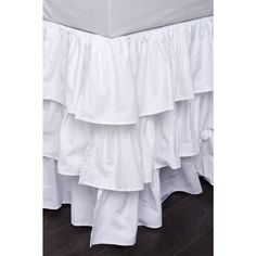 white ruffled bedskirt on wooden floor with dark wood flooring and walls