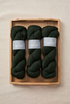 three skeins of green yarn in a wooden box