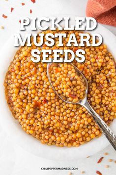 a white bowl filled with cooked mustard seeds on top of a table next to a spoon