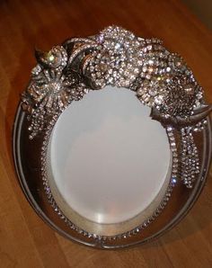 a silver plate topped with lots of jeweled items on top of a wooden table