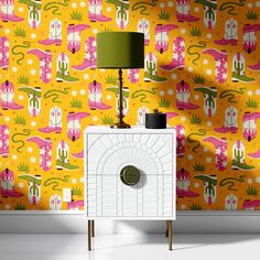 a white cabinet sitting in front of a yellow wallpaper with pink and green designs