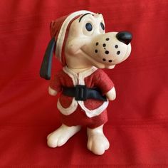 a ceramic dog figurine wearing a red and white outfit on a red background