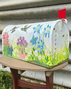 a painted mailbox sitting on top of a wooden bench