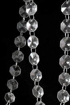 a pair of silver earrings hanging from a black background with white beads and chains attached to them