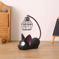 a black cat lamp sitting on top of a wooden table