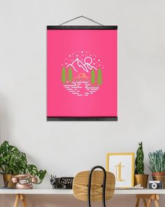 a pink poster hangs on the wall above a desk with a chair and potted plants