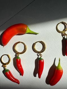 six red peppers are hanging from gold - plated key chains on a white surface