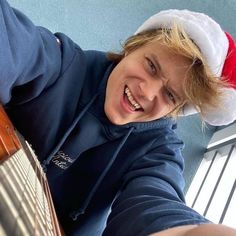 a young boy wearing a santa hat and holding an instrument in his hand while smiling at the camera