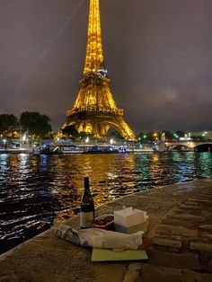 the eiffel tower is lit up at night with food and wine on the ground