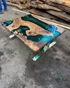 a wooden table with blue and green paint on it sitting in front of some logs