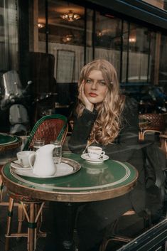 a woman sitting at a table in front of a window