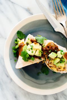 a burrito on a plate with avocado and cilantro