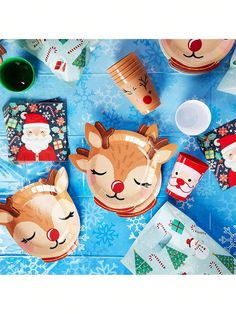 a table topped with plates and cups filled with christmas themed items, including santa's reindeer faces