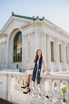 a woman is sitting on a balcony in front of a building with columns and pillars