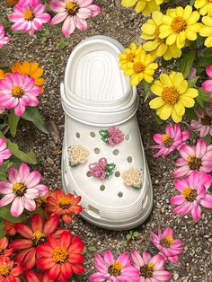 a pair of white crocs surrounded by colorful flowers