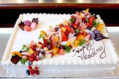 a birthday cake decorated with fruit and butterflies