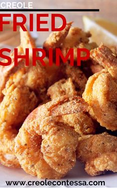 fried shrimp on a white plate with lemon wedges