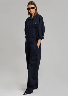 Color: Navy Unisex style Midweight twill fabric Oversized cargo jumpsuit Straight leg Pointed collar  The Frankie Shop logo embroidered on the front and back Elastic tabs at side waist Front flap chest pockets Slant hip pockets Zip and velcro front closure Unlined 65% Polyester 35% Cotton Dry Clean  By The Frankie Shop Casual Workwear Jumpsuit With Flap Pockets, Utility Overalls With Pockets For Workwear, Casual Navy Jumpsuits And Rompers With Pockets, Casual Navy Jumpsuits And Rompers For Workwear, Utility Cotton Cargo Jumpsuits And Rompers, Utility Cotton Jumpsuits And Rompers In Cargo Style, Utility Style Cotton Jumpsuits And Rompers With Cargo Details, Utility Denim Jumpsuit With Patch Pockets For Work, Utility Cotton Jumpsuits And Rompers With Multiple Pockets