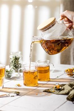 a person pouring tea into cups on a table