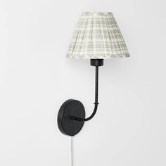 a lamp that is on the wall next to a light fixture with a fabric shade