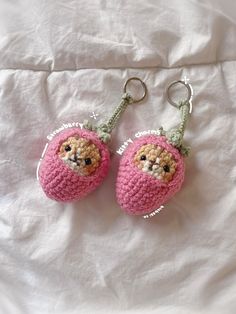 two crocheted keychains with stuffed animals on them sitting on a bed