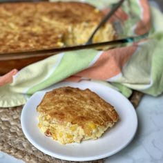 a piece of cornbread on a plate next to a baking pan with a spatula