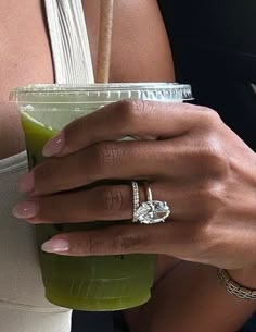 a close up of a person holding a drink with a diamond ring on it's finger