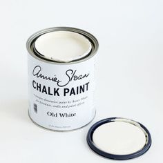 an open can of chalk paint next to a small black and white object on a white surface