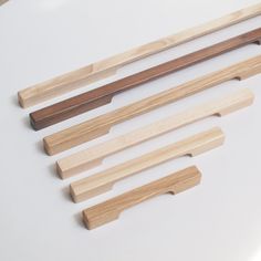 five wooden dowels are lined up on a white surface