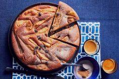 a pie with slices cut out and two cups of coffee on the side next to it