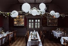 an empty dining room with white paper lanterns hanging from the ceiling and tables set for dinner